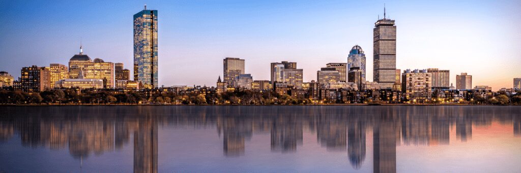 City skyline reflecting on calm water at sunset.