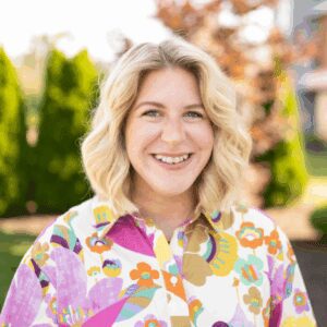 Smiling woman in colorful shirt outdoors.