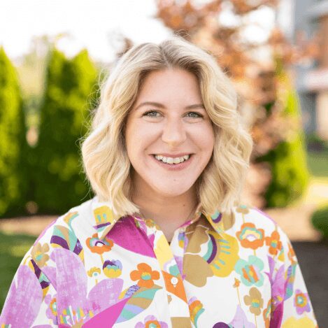 Smiling woman in colorful shirt outdoors.
