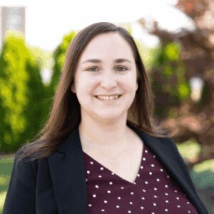 Smiling woman outdoors in professional attire.
