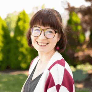 Smiling woman with glasses in garden.