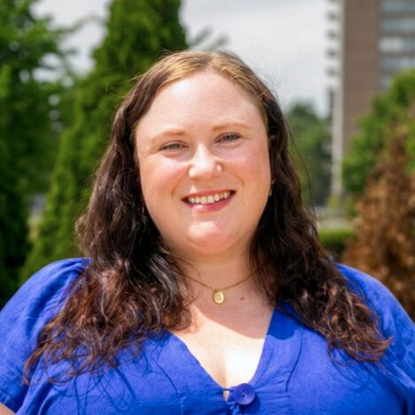 Smiling woman with long hair in blue top.