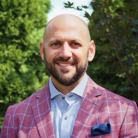 Smiling man in plaid suit outdoors.